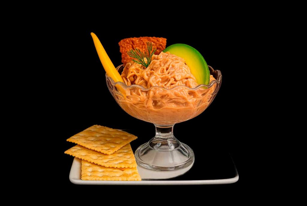 Porción gourmet de ceviche de lechona con aguacate, mango, crocante y galletas de sal, ideal como entrada en Bogotá.